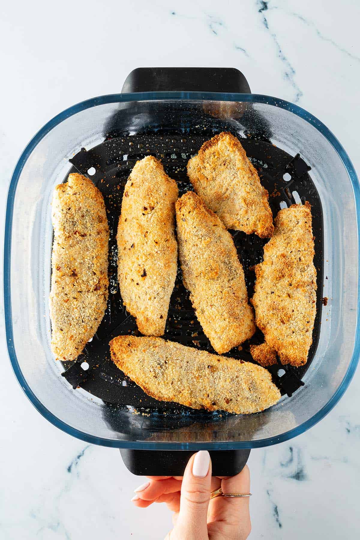 Frisch gebackene, goldbraune, panierte Fischfilets im Airfryer-Korb.