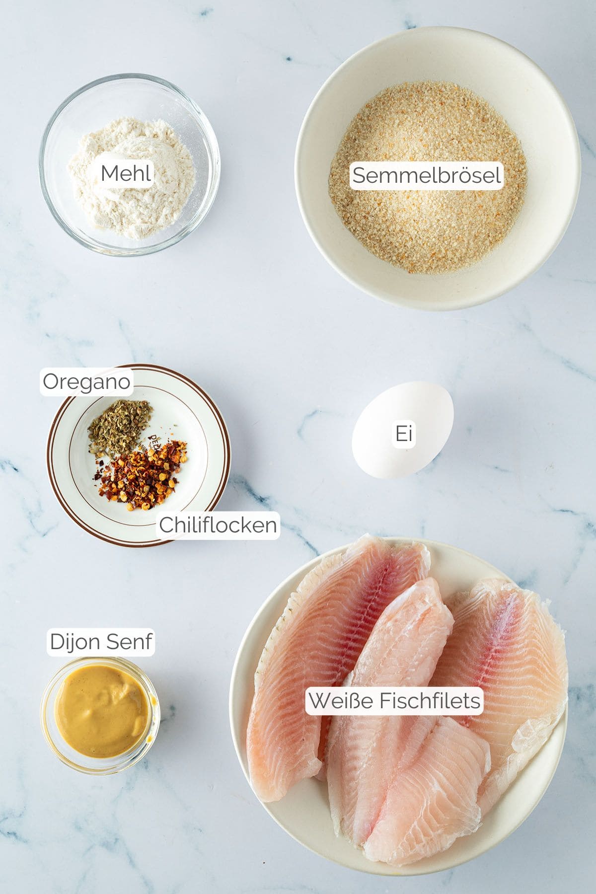 Alle Zutaten mit jeweiligen Textbeschriftungen, die für panierten Fisch aus dem Airfryer benötigt werden.