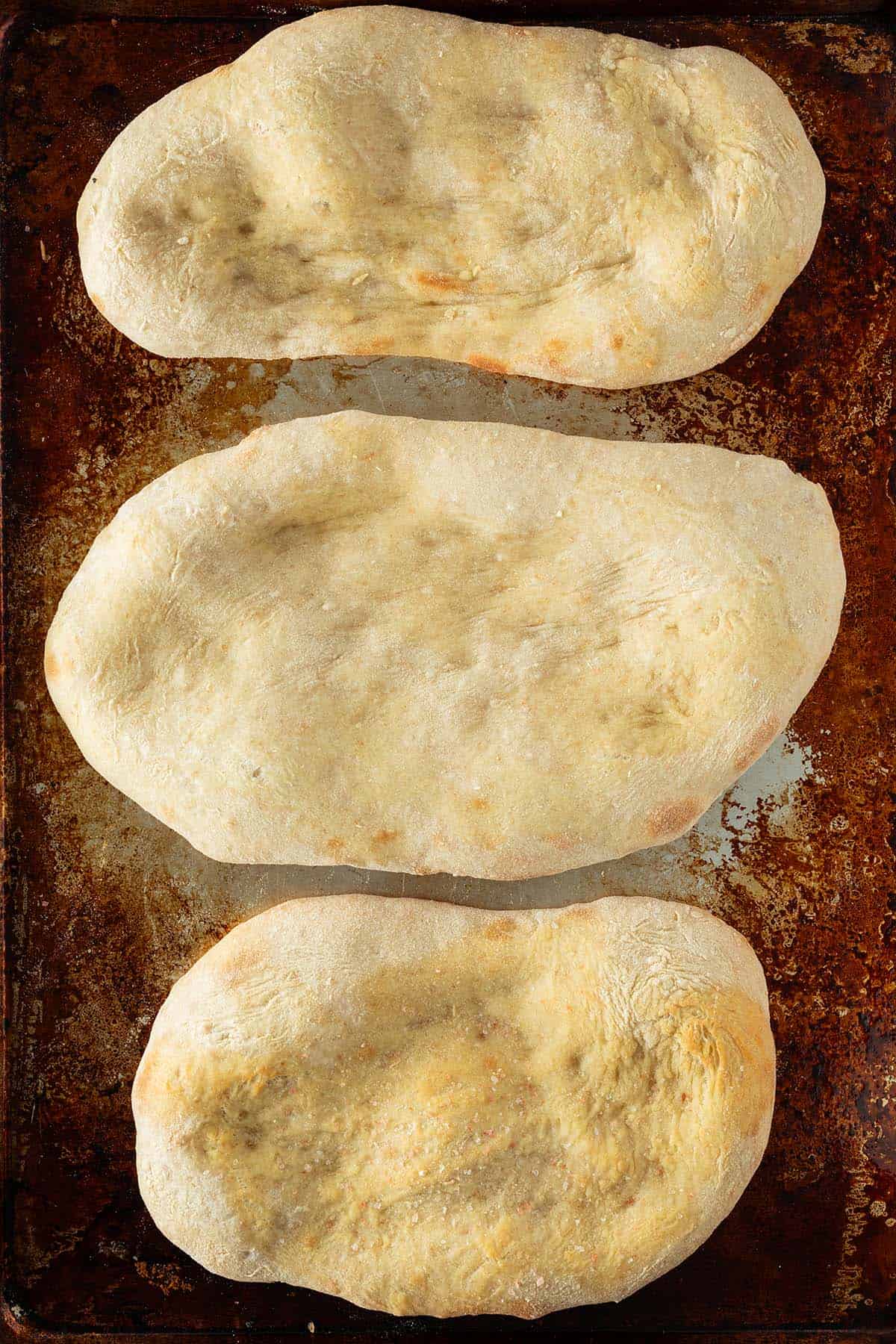 Drei vorgebackene Pinsa B&ouml;den auf einem Backblech.