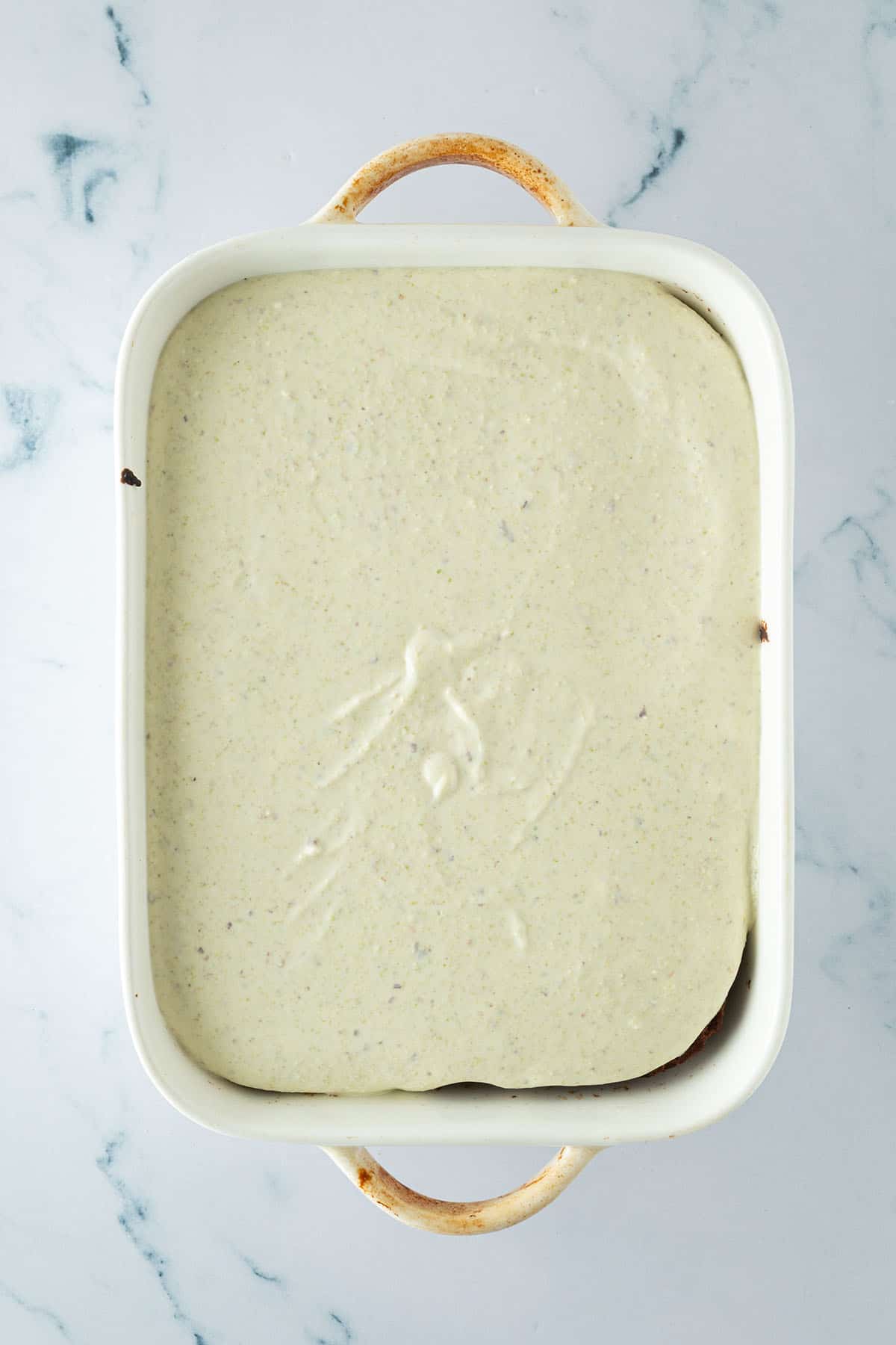 Pistazien Baked Oatmeal in einer Auflaufform mit cremiger Pistazien-Schicht auf Schoko Baked Oats vor dem K&uuml;hlen.