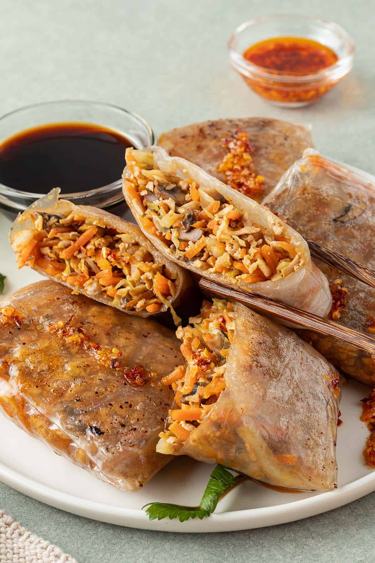 Ein Teller mit Reispapier Dumplings und zwei Dips.