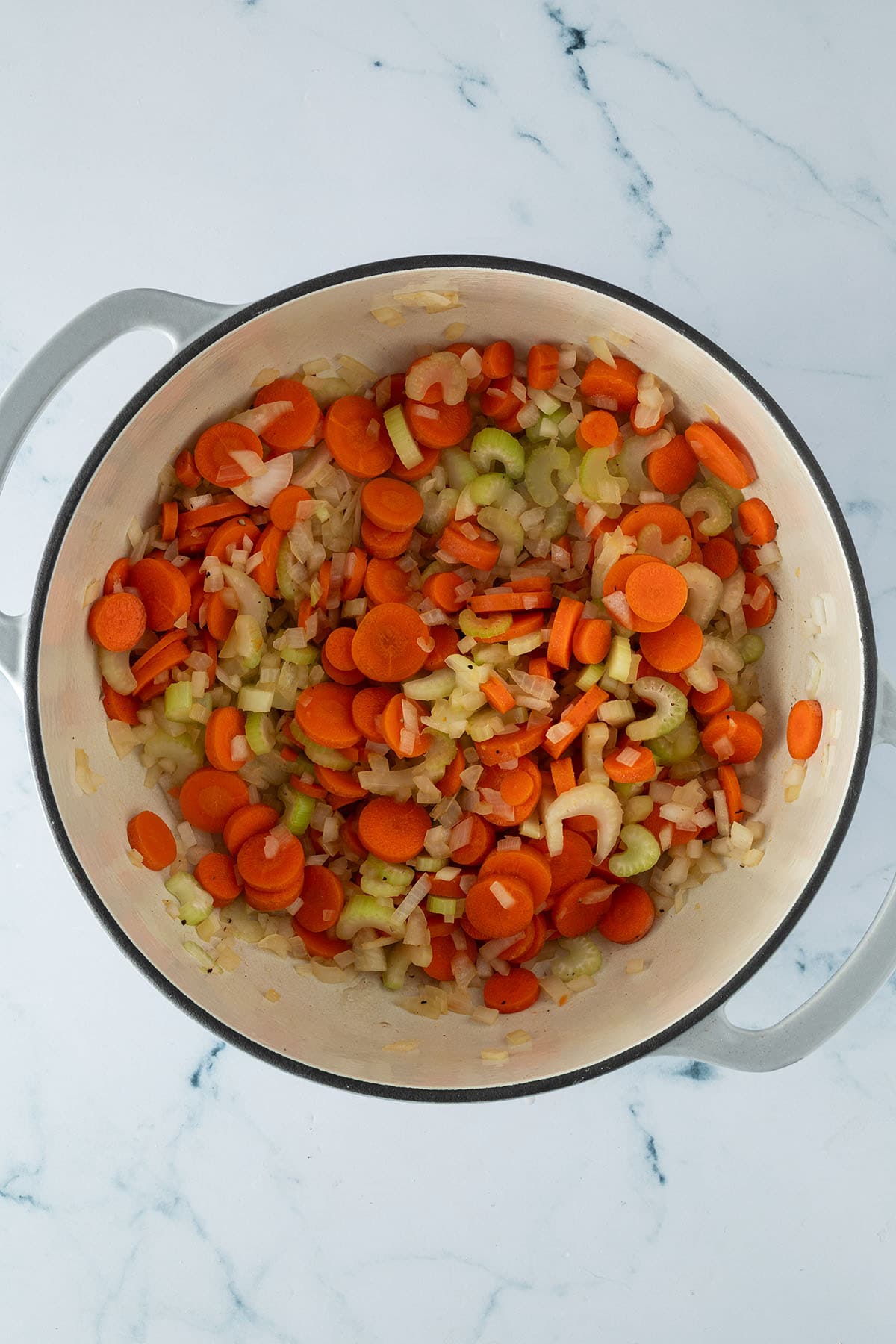 Karotten, Sellerie und Zwiebeln werden im Topf angebraten.