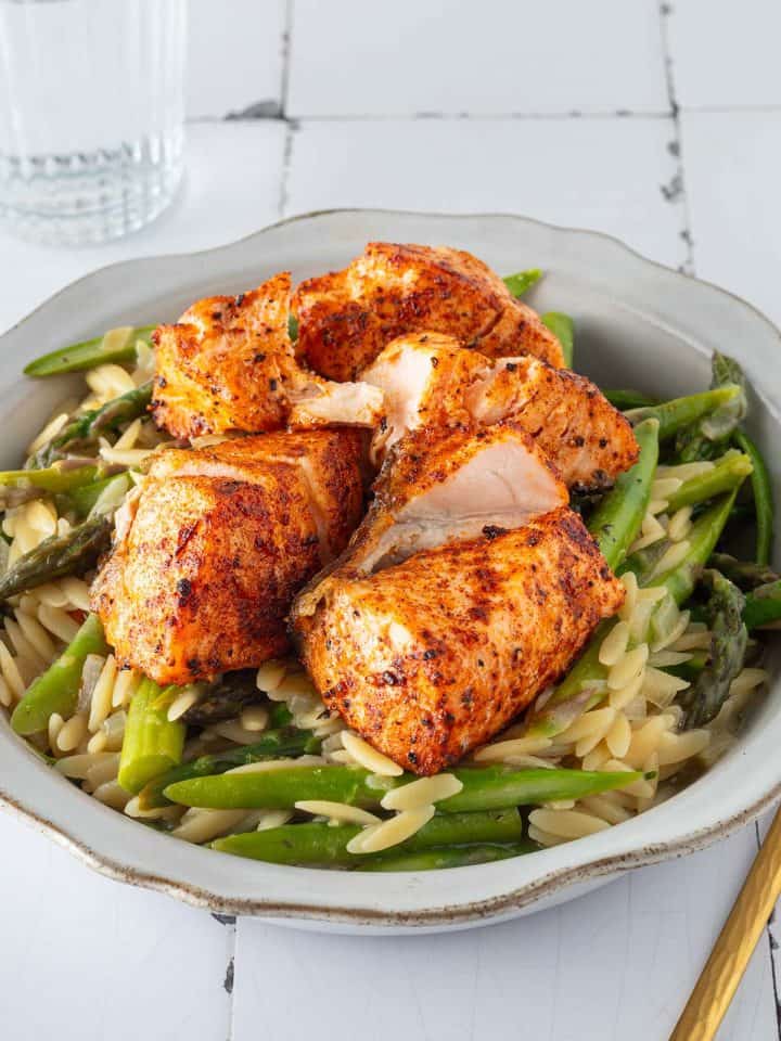 Ein Teller Spargel Lachs Pasta bestehend aus Orzo Nudeln und Spargel in einer cremigen Parmesansauce, getoppt mit Lachswürfeln.