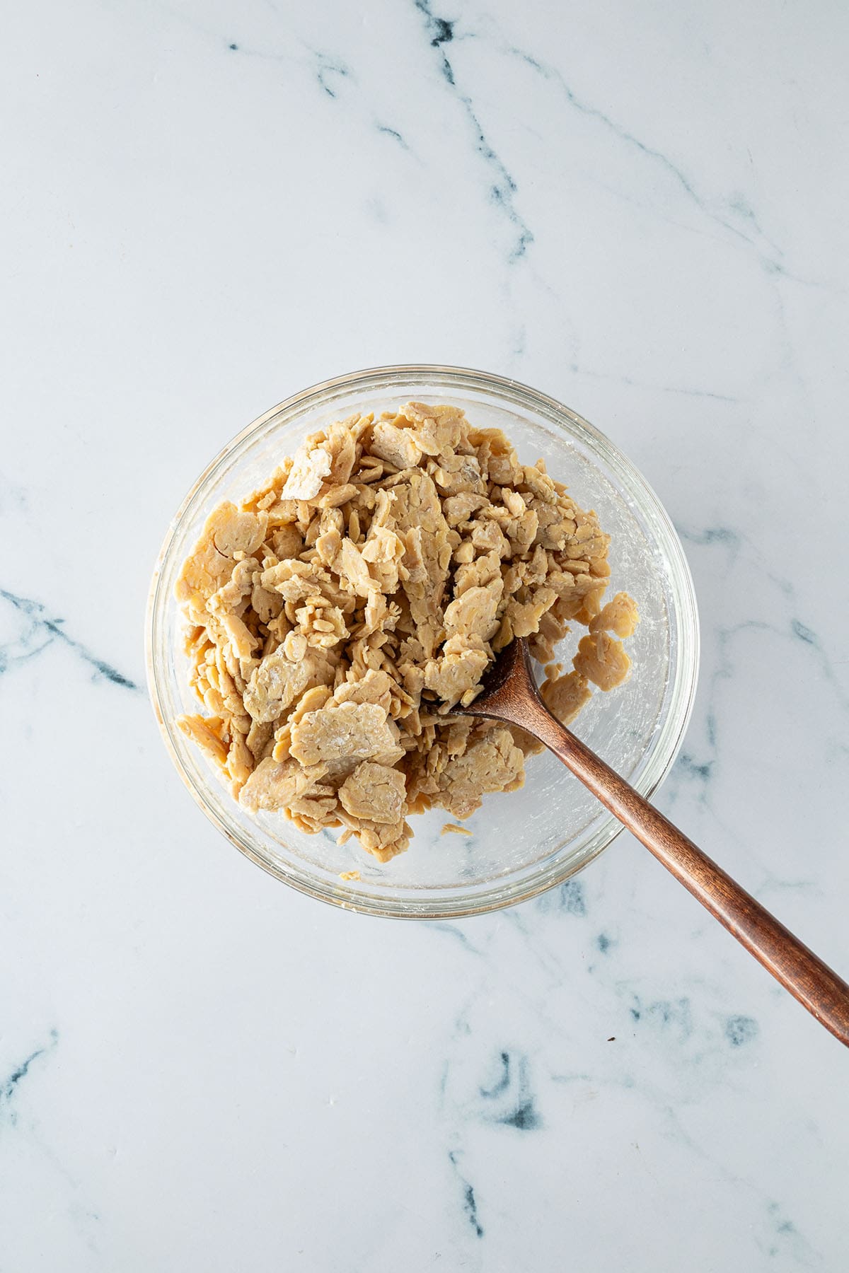 D&uuml;nn gehobelte Tempeh-Scheiben werden in einer Sch&uuml;ssel mit Speisest&auml;rke vermischt.