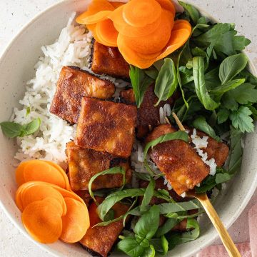 Tempeh Bowl mit frischen Kräutern, Reis, Karotten und knusprigen Erdnuss-Tempeh.