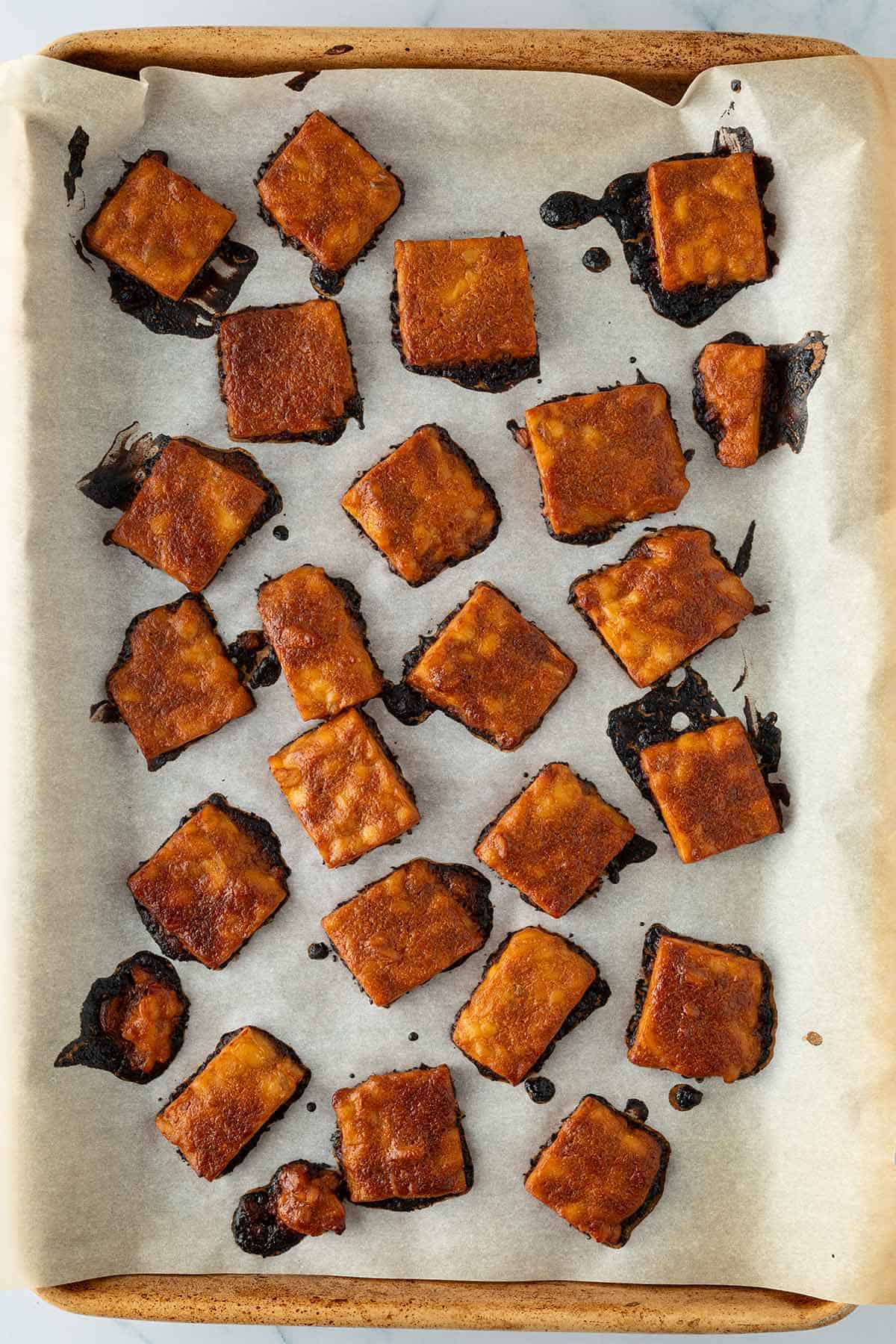 Gebackene Tempeh-Stücke auf einem Backblech.