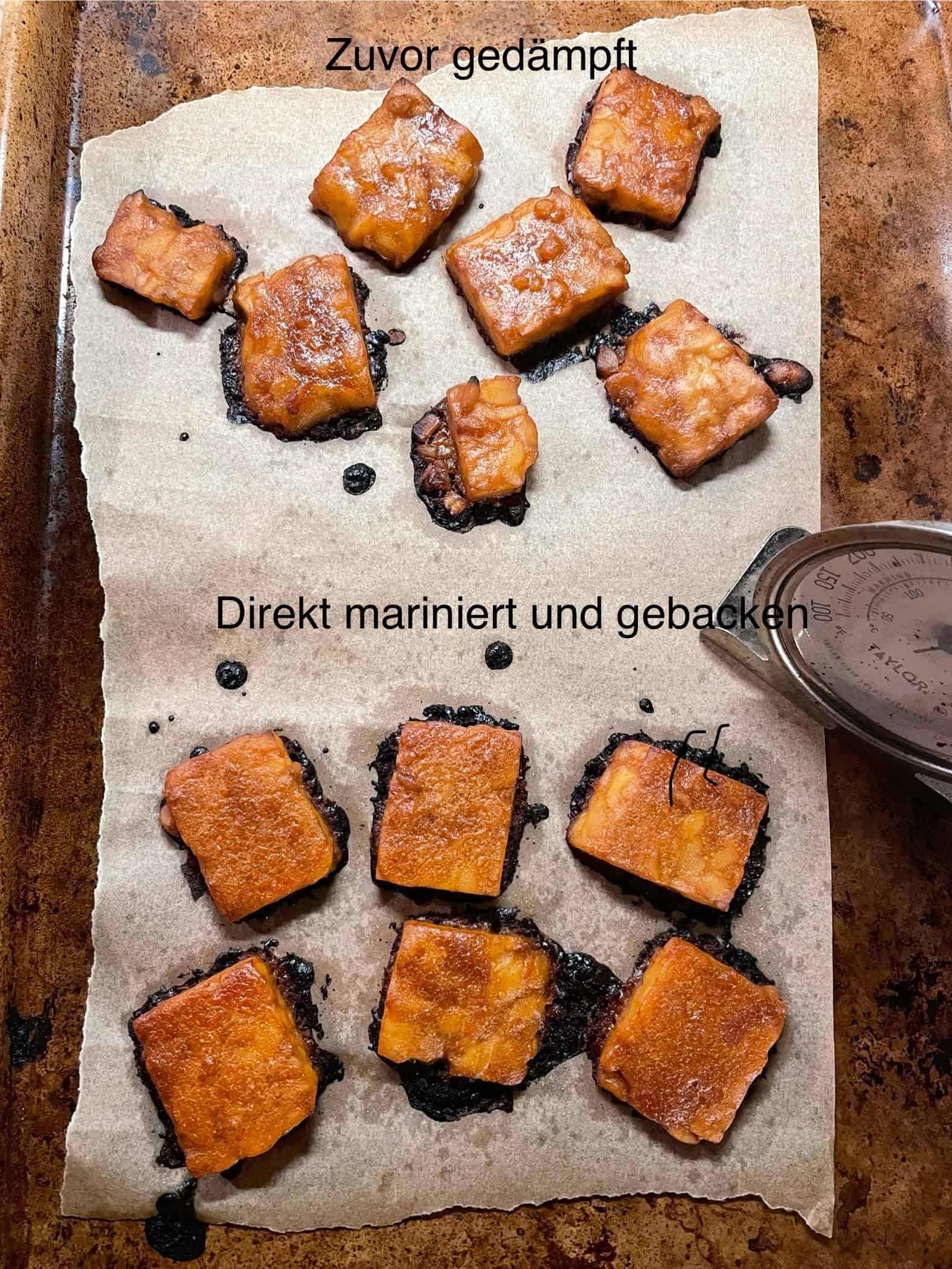 Im Ofen gebackene Tempeh Scheiben auf einem Blech, die Hälfte wurde zuvor noch gedämpft.