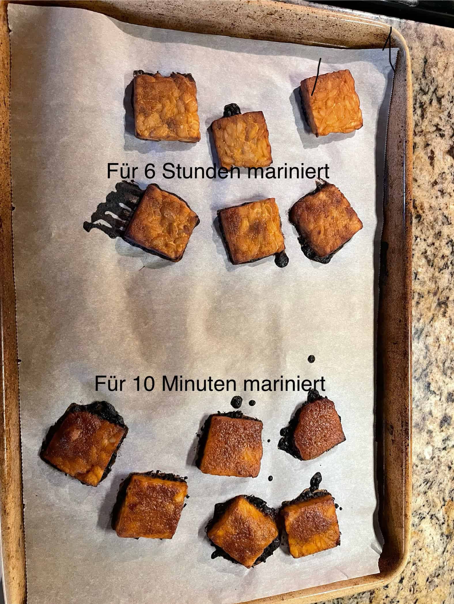 Im Ofen gebackene Tempeh Scheiben auf einem Blech, die unterschiedlich lange mariniert wurden.