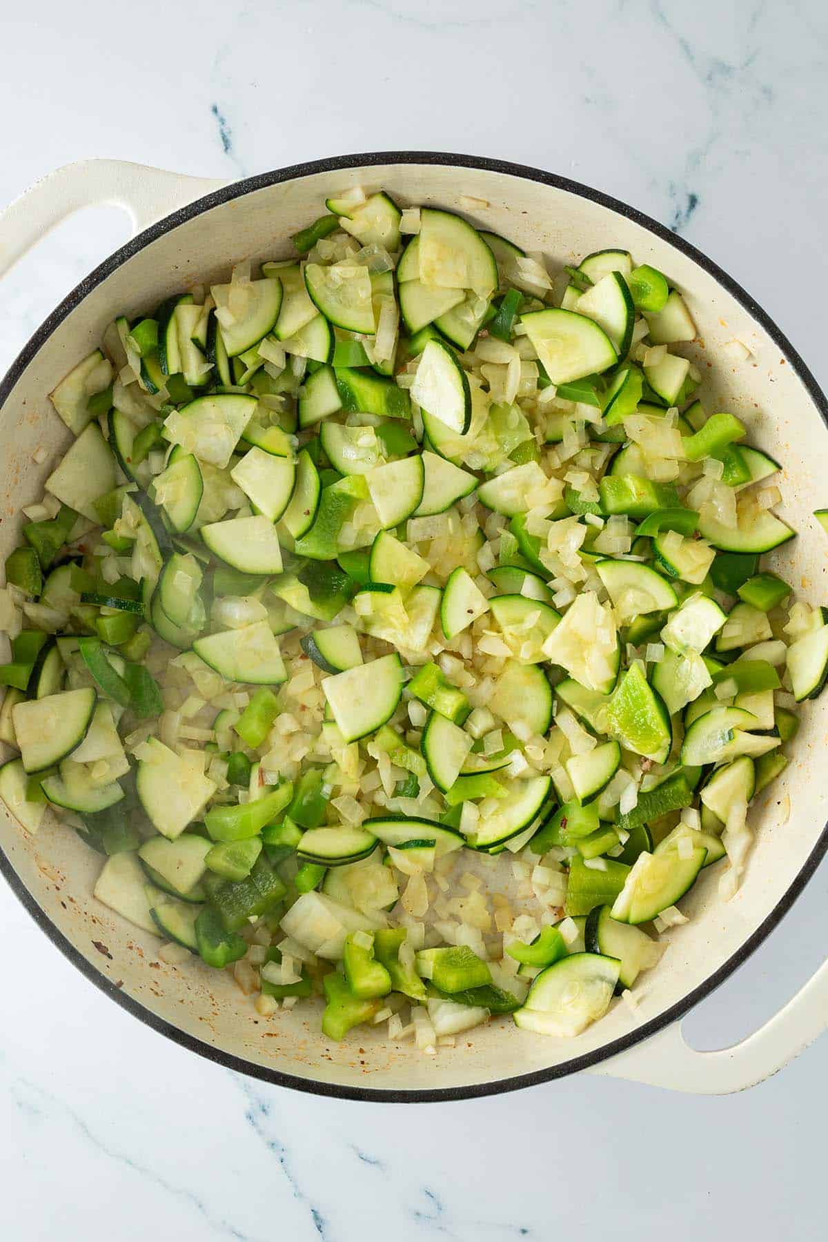 Pfanne mit frisch angedünstetem Gemüse aus gewürfelter Zucchini, Paprika und Zwiebeln.