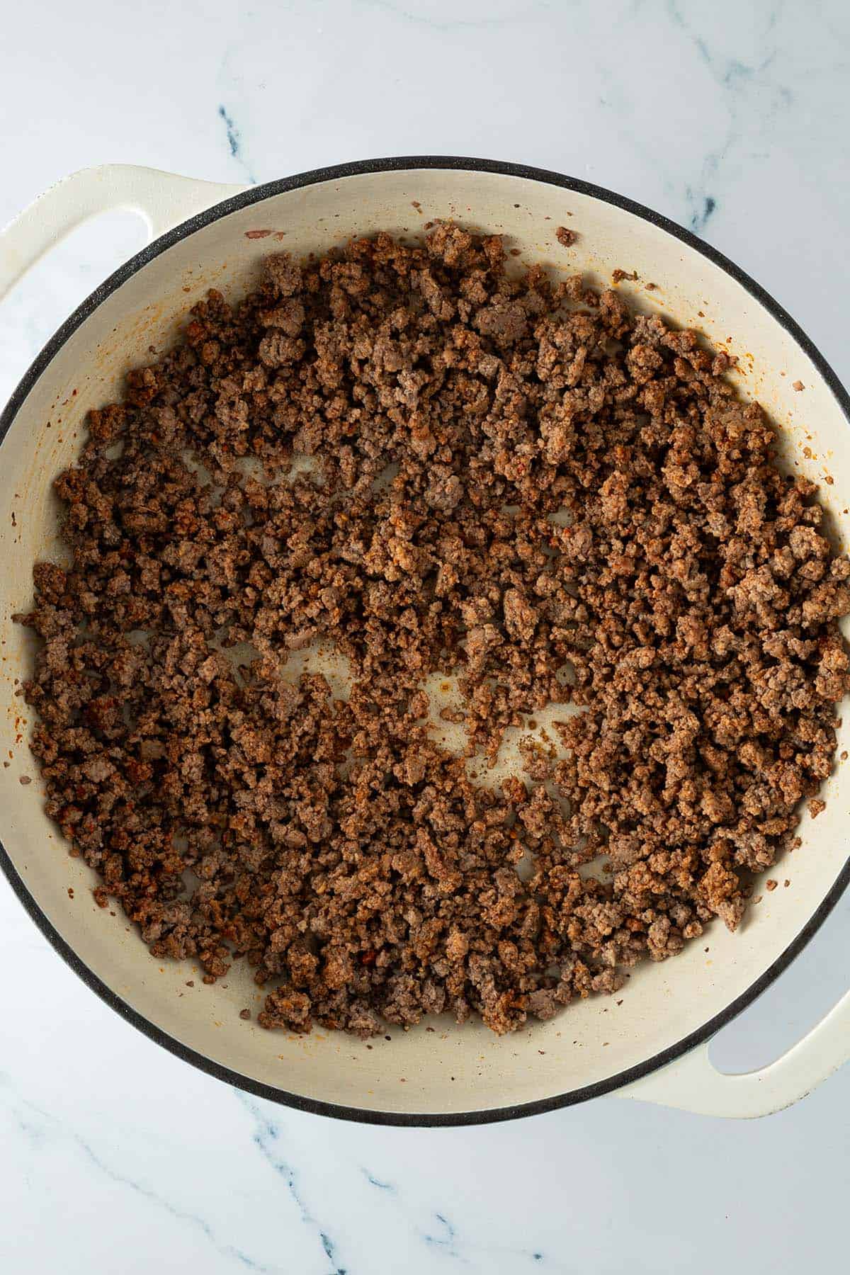 Pfanne mit krümelig angebratenem Hackfleisch gleichmäßig verteilt über den Pfannenboden.