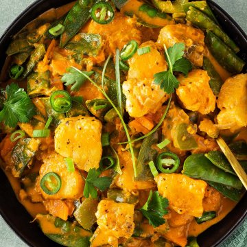 Thailändisches Curry mit Frischstückchen, Gemüse und einer cremigen Sauce wird serviert mit frischen Kräutern.