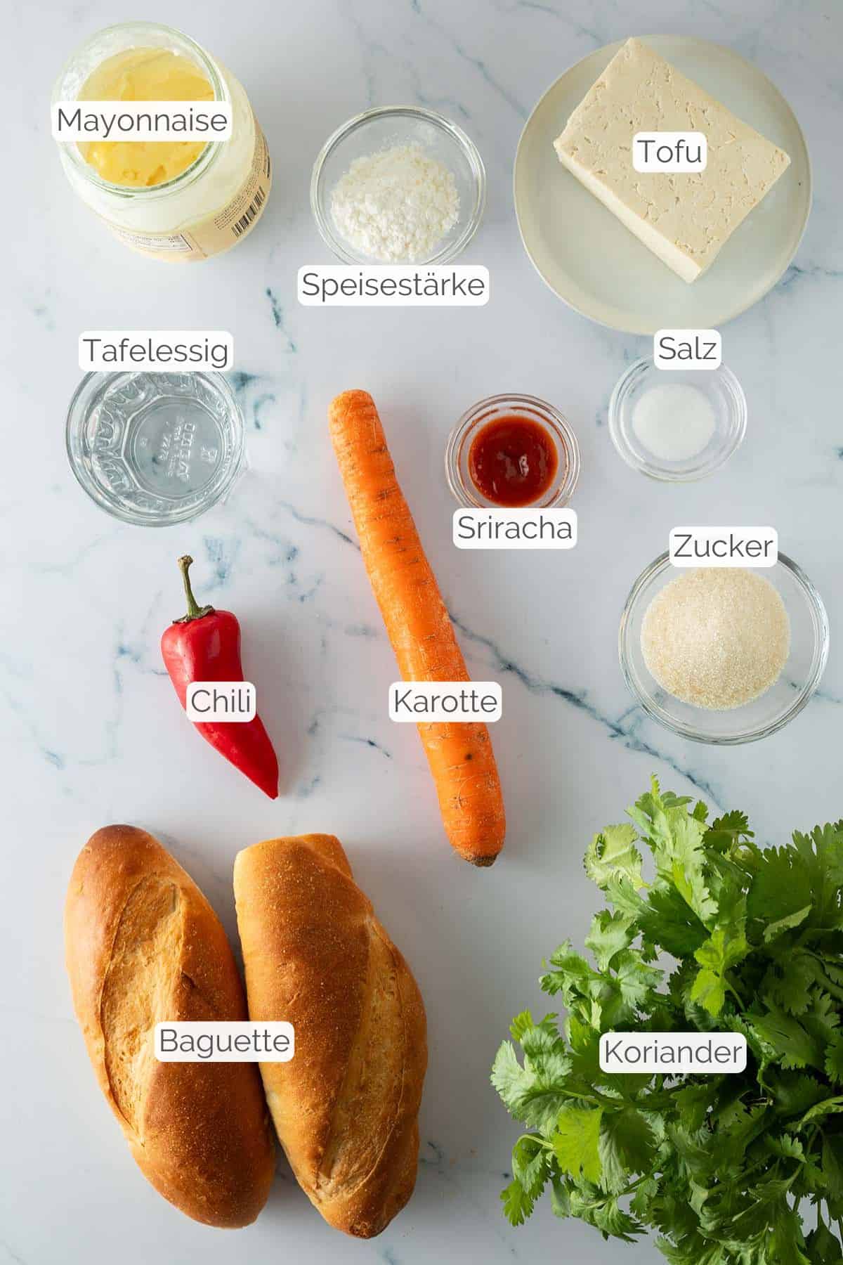 Zutaten mit jeweiligen Textbeschriftungen, die für das vegetarische Banh Mi mit Tofu benötigt werden.