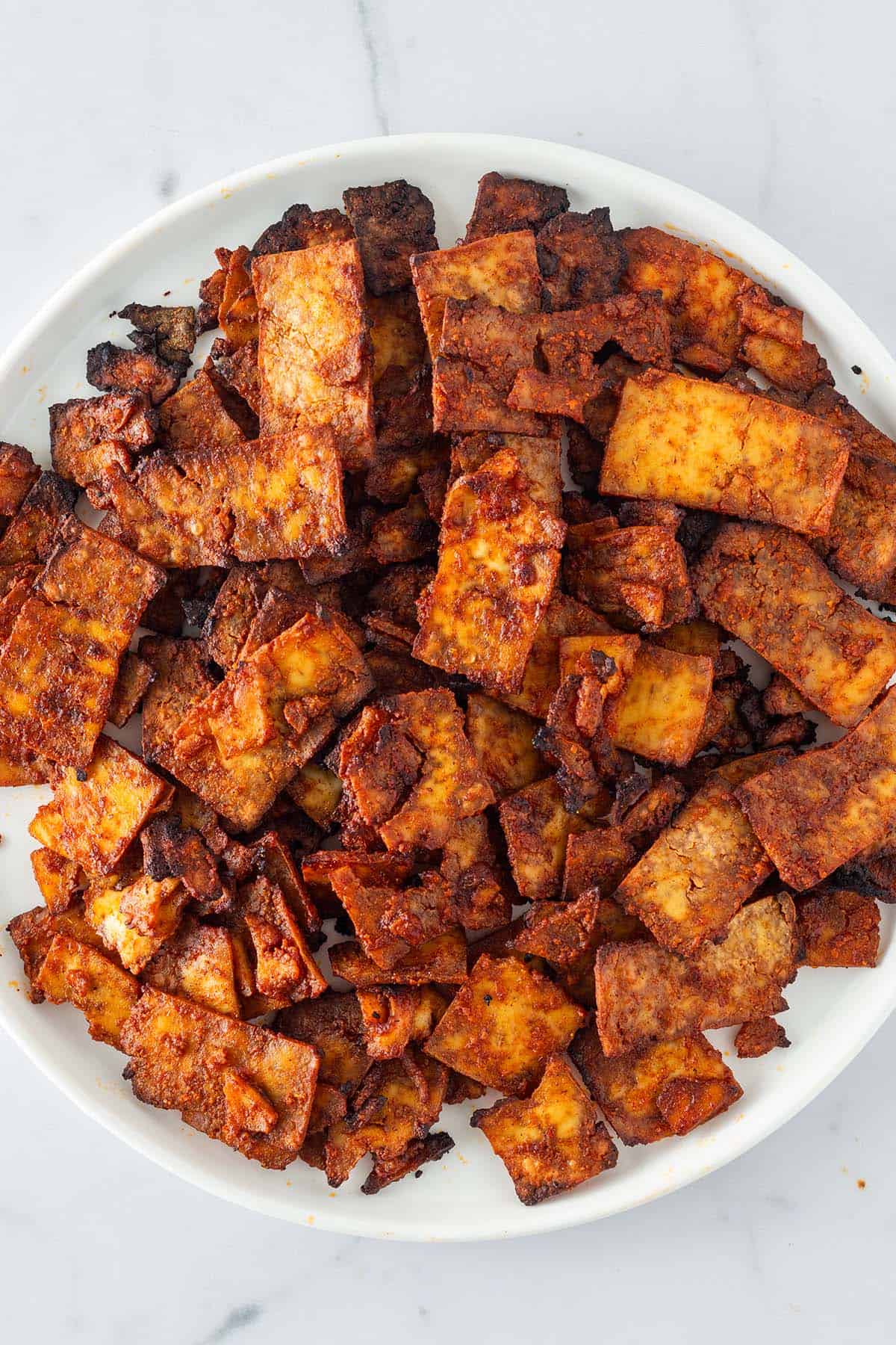 Knusprig gebackene Tofu-Gyros-Streifen auf einem weißen Teller.