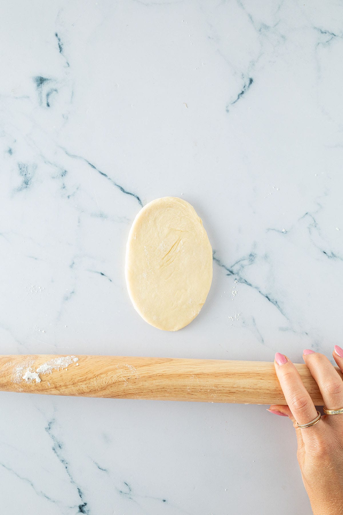 Tortilla Kugel auf einer Arbeitsfl&auml;che, nachdem man mit dem Nudelholz einmal von der Mitte aus hoch und runter gerollt hat.
