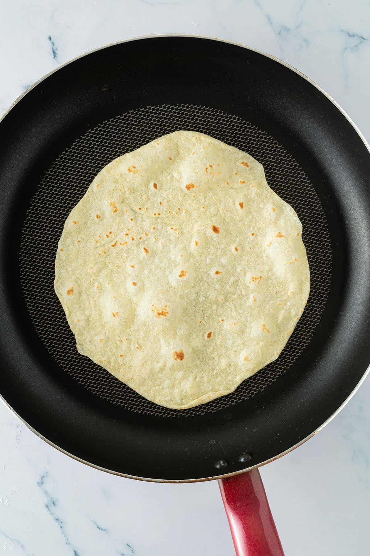 Selbstgemachter Tortilla in einer Pfanne, leicht gebr&auml;unt mit kleinen braunen Flecken.