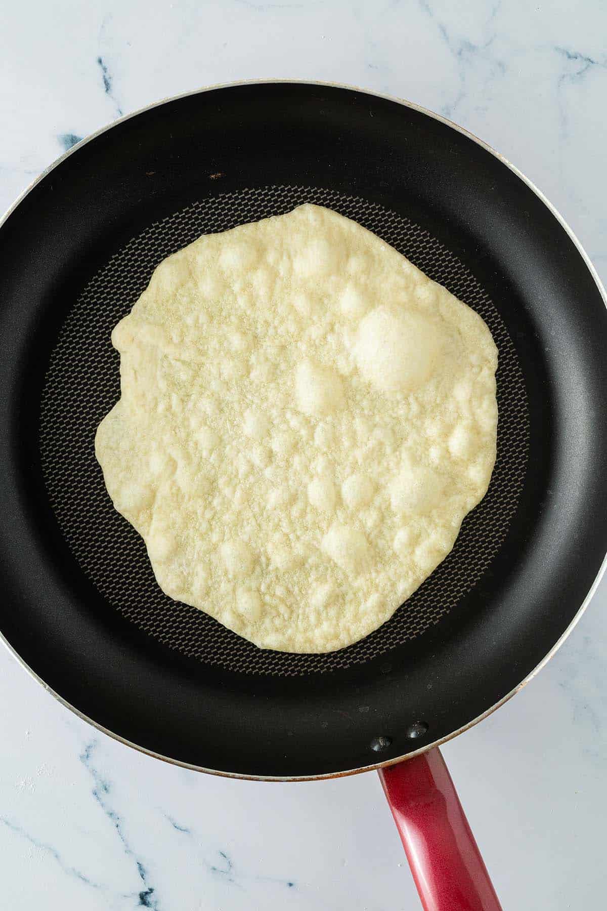 Tortilla wird in der Pfanne ausgebacken. Die gro&szlig;en Luftblasen symbolisieren, dass er jetzt gewendet werden kann.