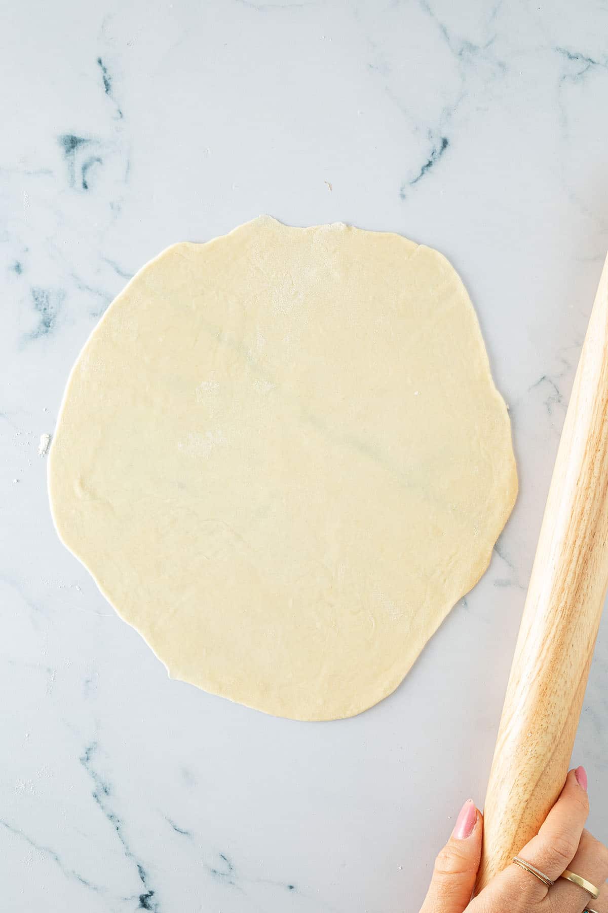 D&uuml;nn ausgerollter Tortilla-Teig auf einer Arbeitsfl&auml;che mit Nudelholz.