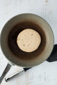 Pancake in einer Pfanne die kleinen Blasen auf der Oberfläche und der leicht braune Rand des Pancakes zeigen an, dass er breit zum wenden ist