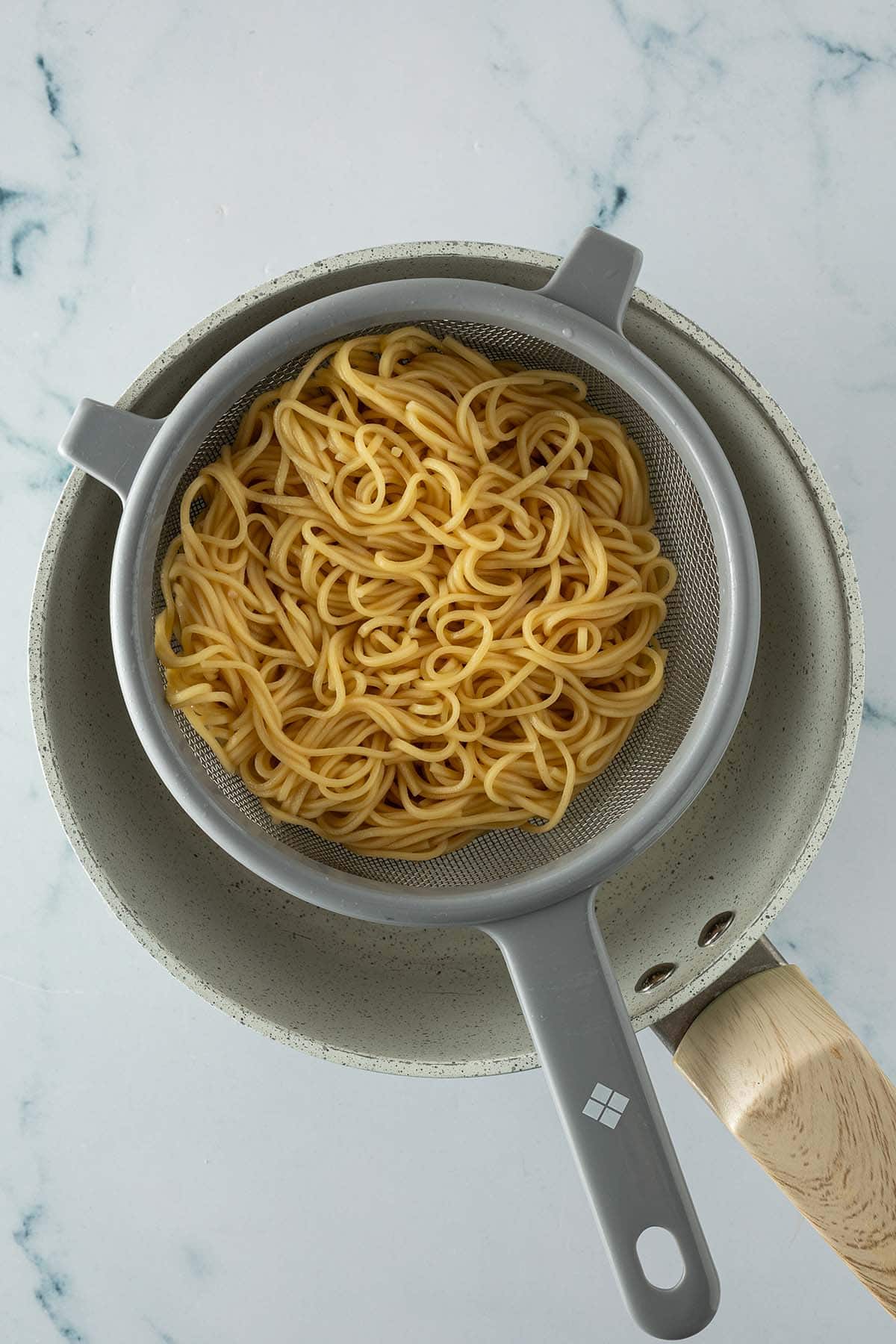 Gekochte Ramen-Nudeln in einem Sieb &uuml;ber einem Topf, frisch abgegossen.