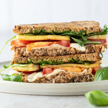 Tofu Sandwich mit Tomate und Mozzarella vor weißem Hintergrund.