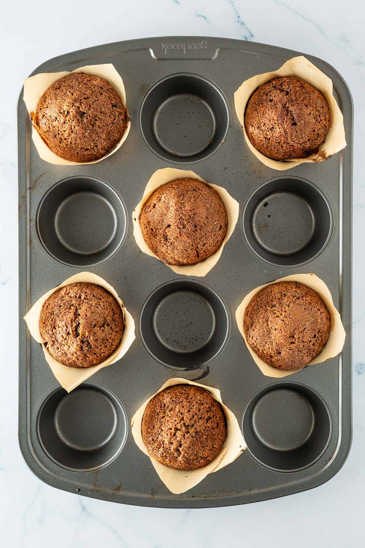 Frisch gebackene Schoko Zucchini Muffins im Muffinblech mit Backpapierförmchen.