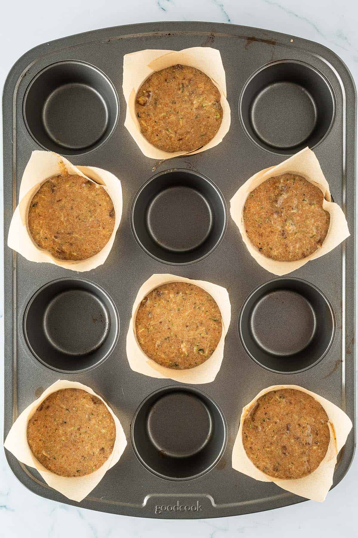 Schoko Zucchini Muffin Teig in mit Backpapier ausgelegten Muffinformen vor dem Backen.