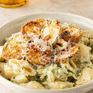 Cremige Zucchini Pasta mit Ricotta und knusprigen Zucchini-Chips, serviert mit frisch geriebenem Parmesan.