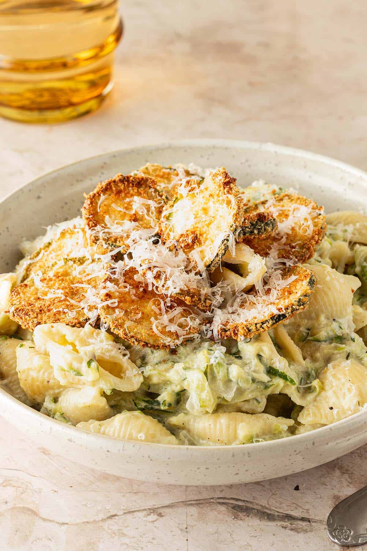 Cremige Zucchini Pasta mit Ricotta und knusprigen Zucchini-Chips, serviert mit frisch geriebenem Parmesan.