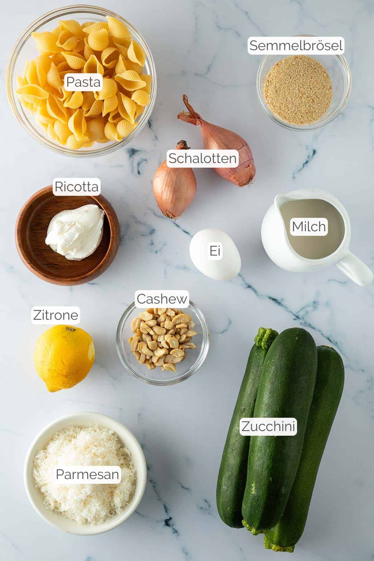 Alle Zutaten mit jeweiligen Textbeschriftungen, die für die Zucchini Pasta benötigt werden.